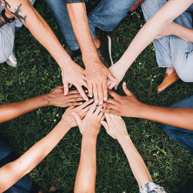 Students put their hands together in a circle