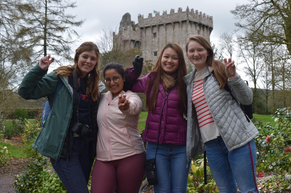Students smile in front of a castle in Ireland