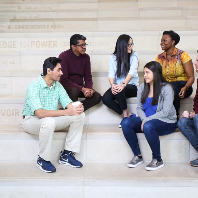 Students sit together on the steps of the library