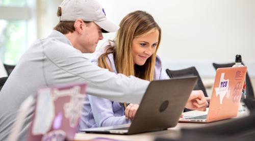 Two students work on a laptop