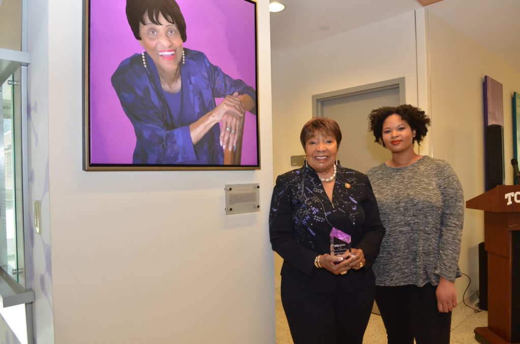 Two people standing next to a digital portrait.